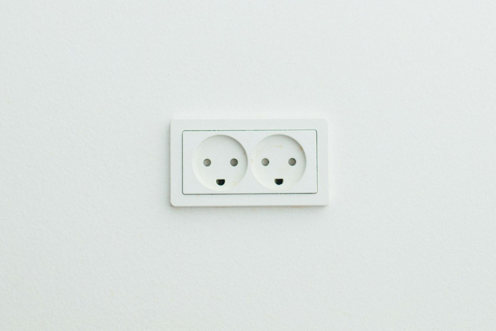 Weiße Aufputz-Steckdose auf einer Wand, die leicht schief sitzt