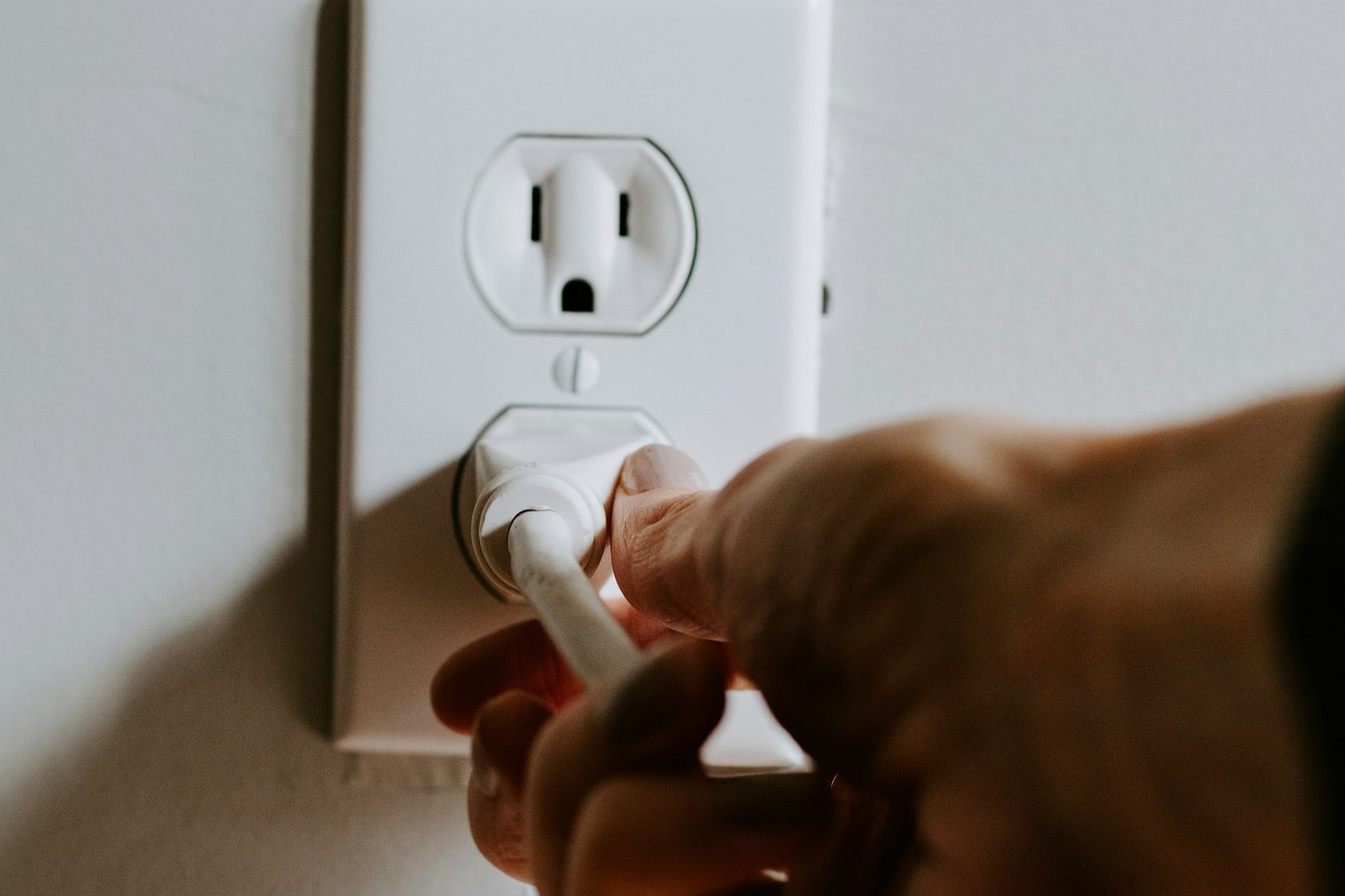 Person arbeitet mit Schraubendreher an einer geöffneten Steckdose in der Wand