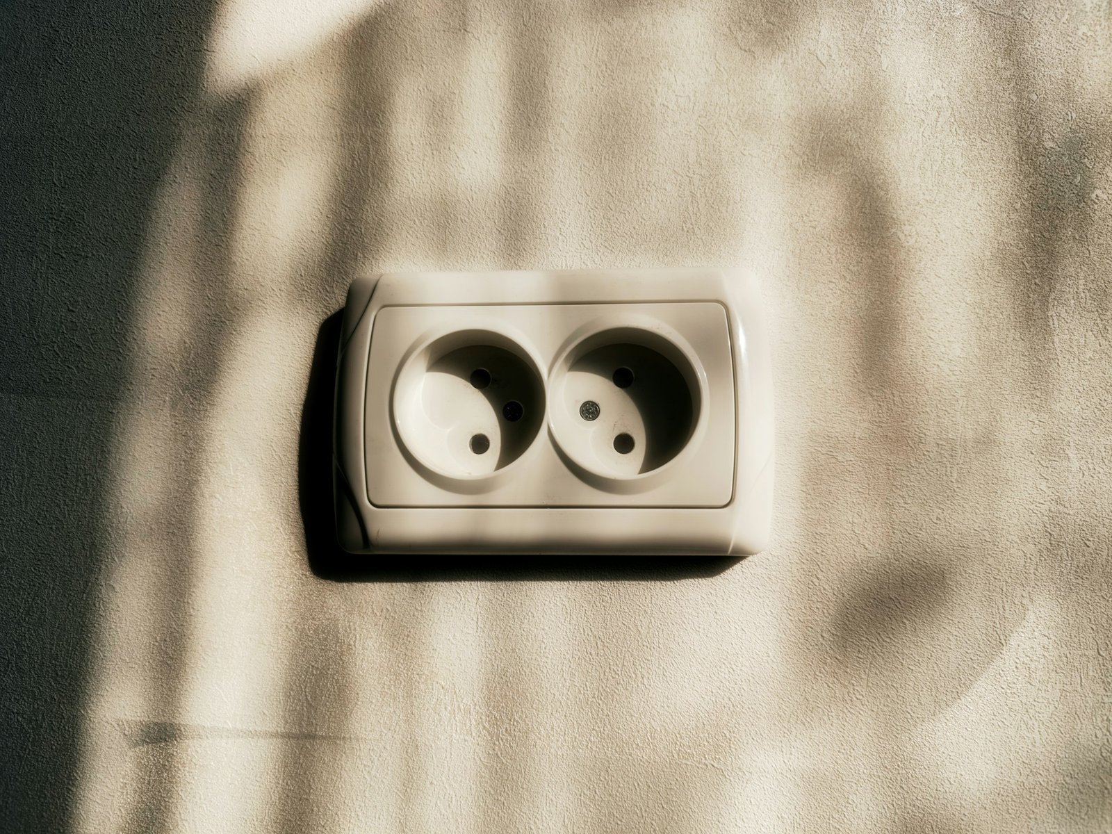 Locker sitzende Steckdose in einer weißen Wand mit leichtem Spalt