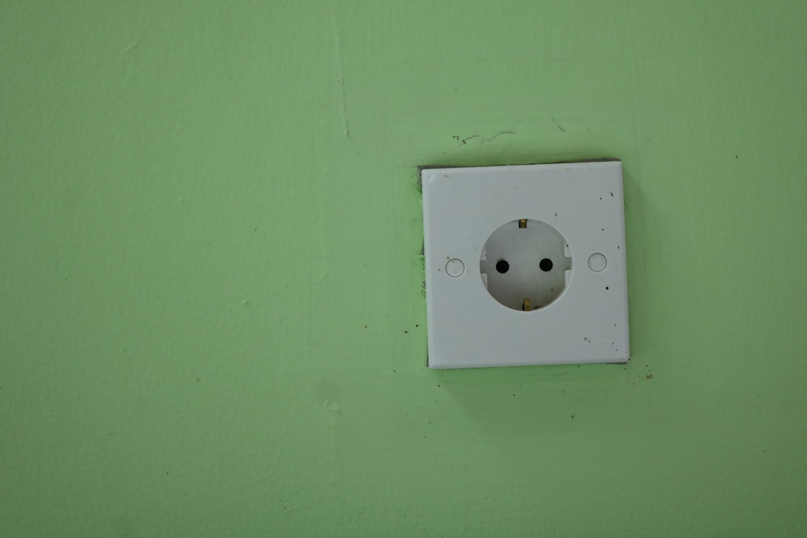 Steckdose, die sichtbar schief in einer weißen Wand sitzt