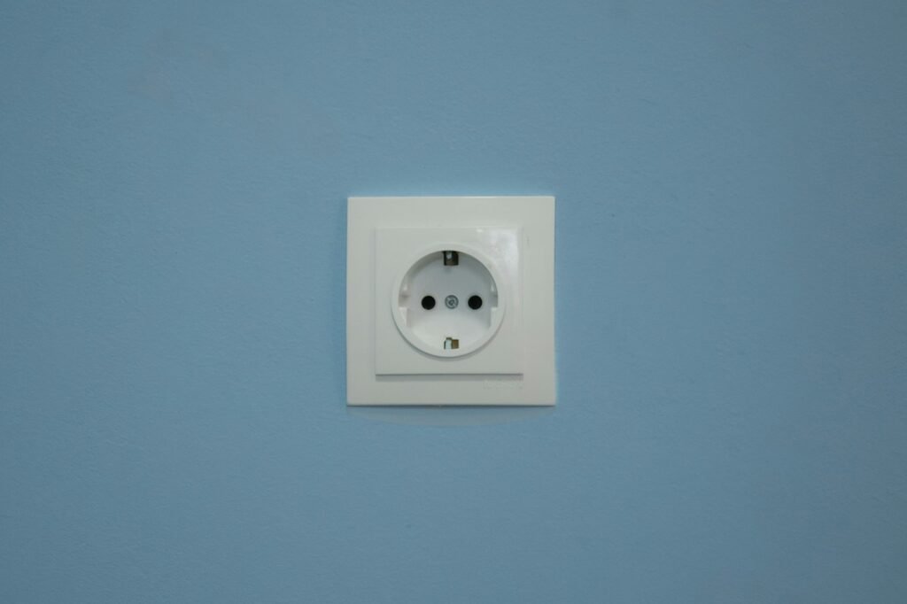 Steckdose mit leicht gelöstem weißen Rahmen an einer Wand